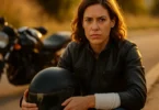 Injured woman motorcyclist holding her helmet after a crash