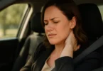 Woman in a car holding her neck in pain from whiplash